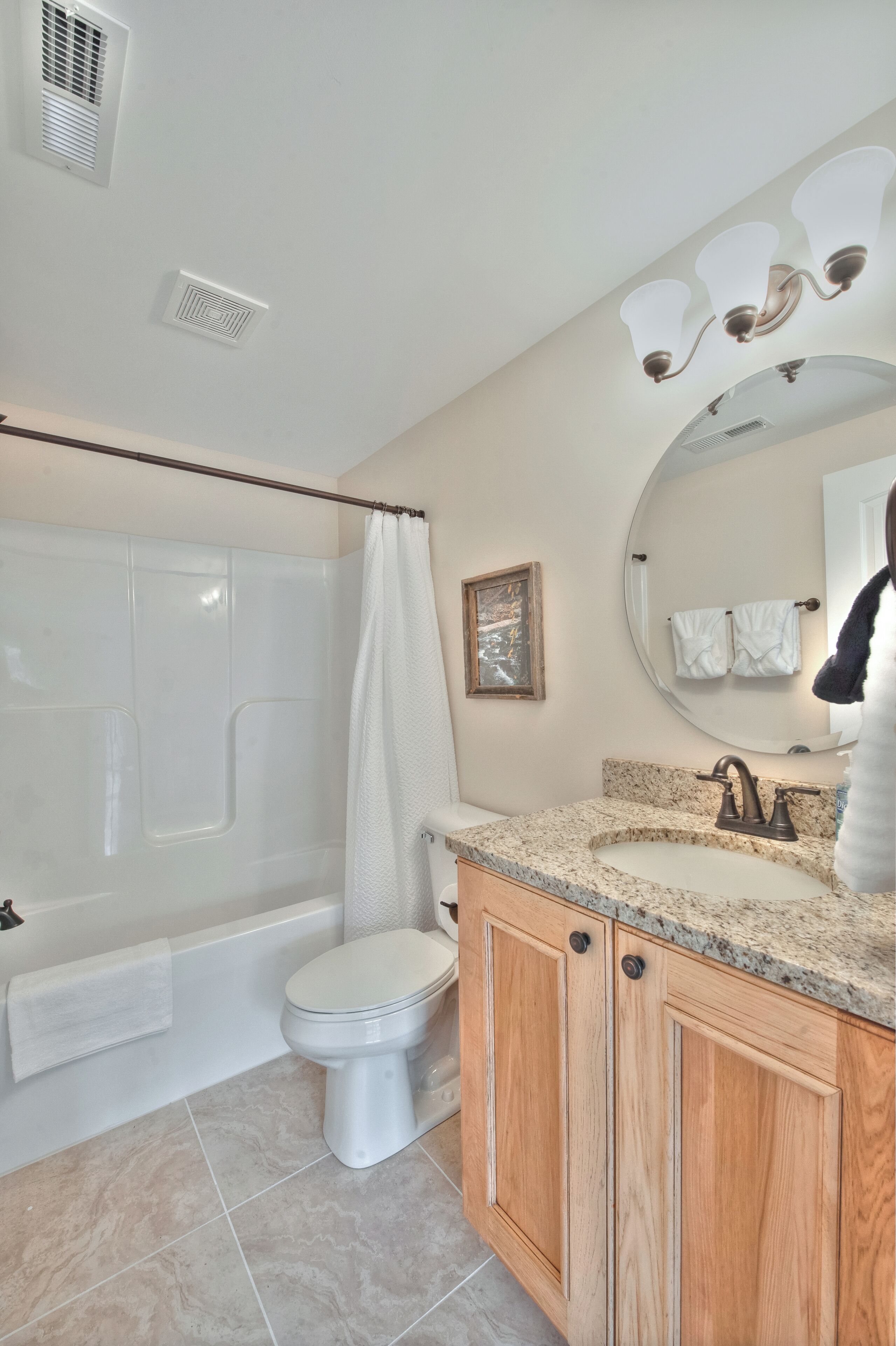 A bathroom with a bathtub, toilet, vanity with a sink, and a shower curtain.