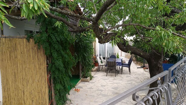 Un'area patio con tavolo e sedie, immersa nel verde e circondata da una recinzione in bambù.