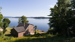 Una casa con techo inclinado, una chimenea y vistas a un lago.