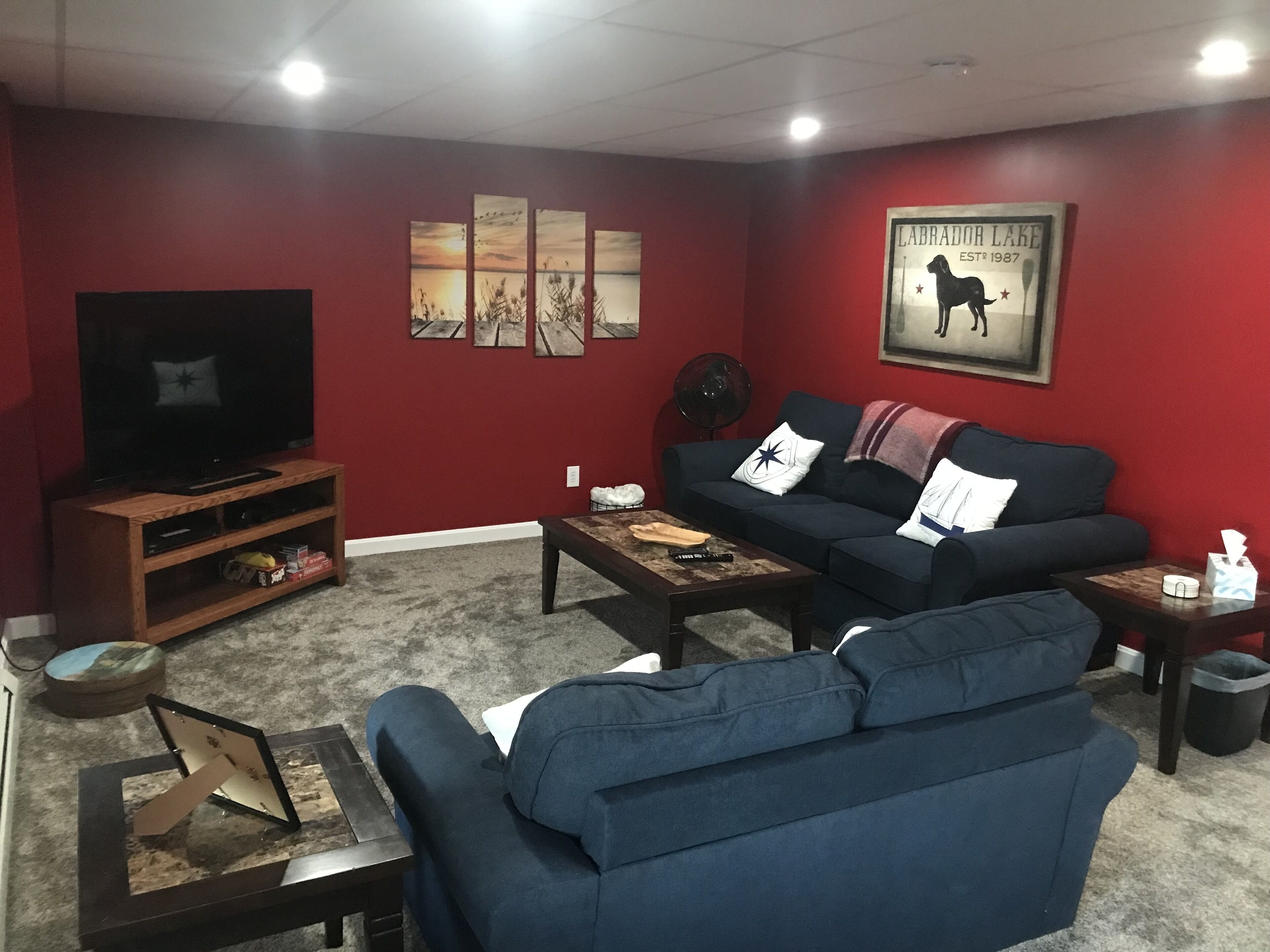 A living room with a TV, a couch, a coffee table, and artwork on the wall.