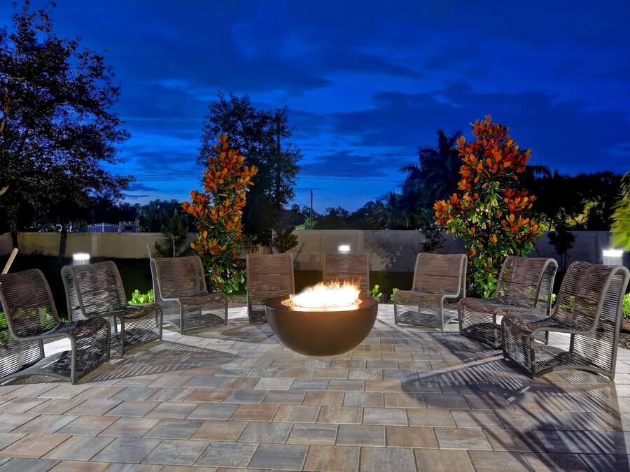 An outdoor seating area with a central fire feature and chairs arranged around it.