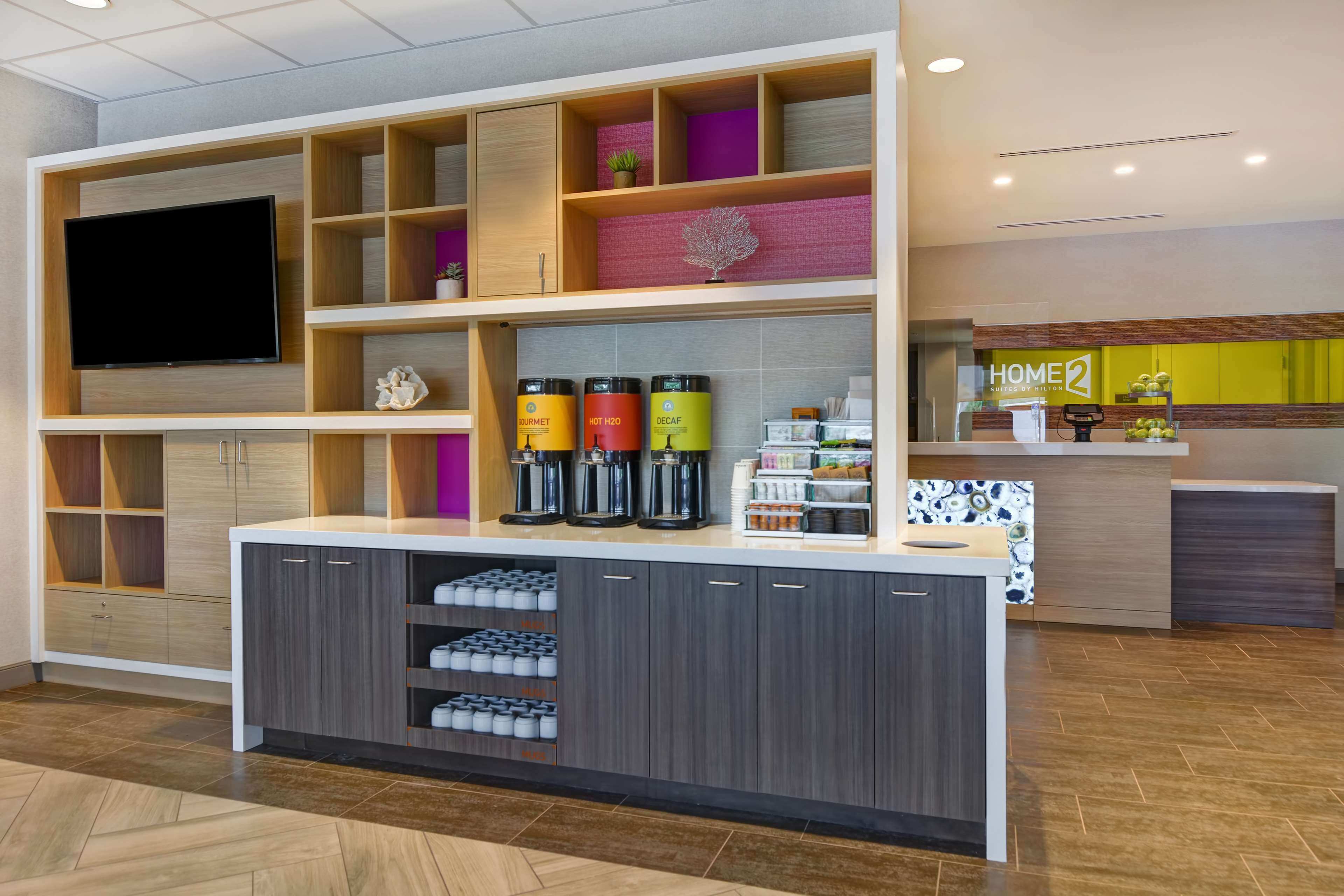 A modern kitchen with built-in appliances, a large TV, and a coffee station.
