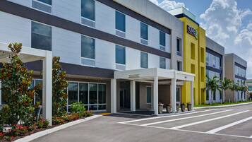 A modern hotel with a covered entrance, large windows, and a yellow accent wall.