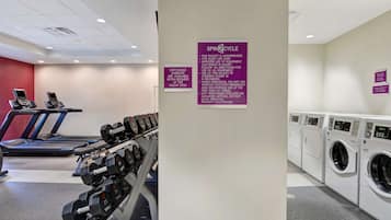 A gym with treadmills, dumbbells, and a washing machine area.