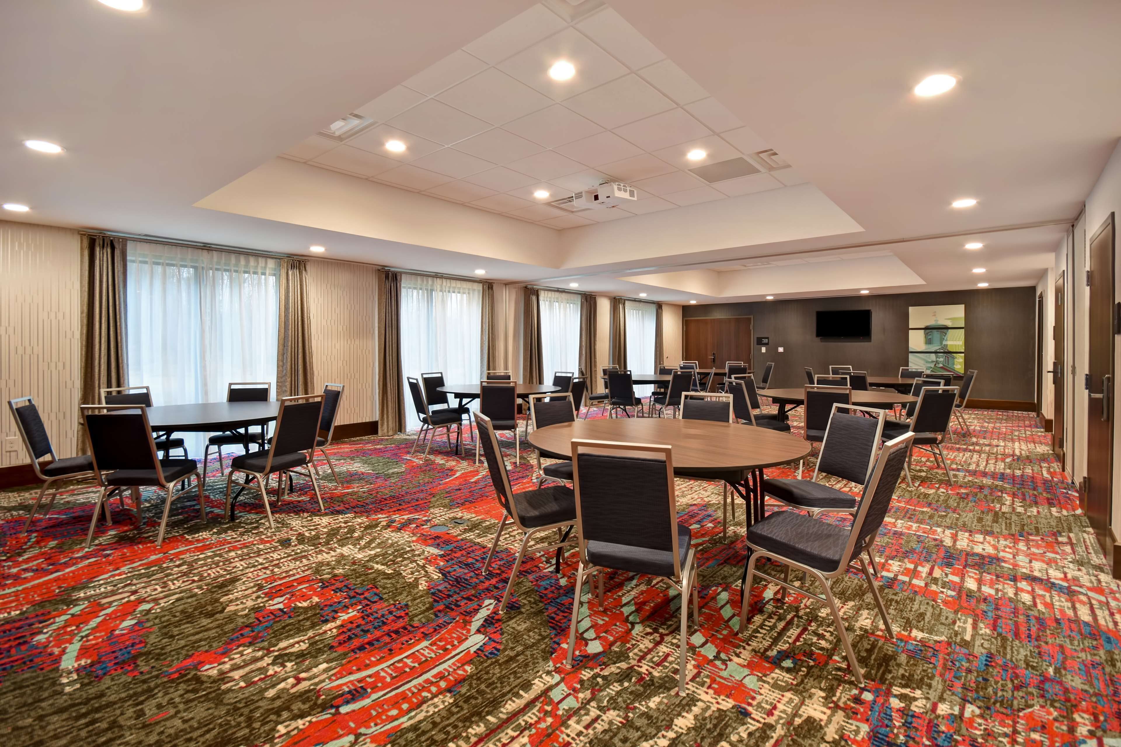 A conference room with a large carpeted floor, multiple tables, and chairs.