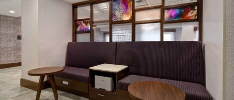 A seating area with a sofa, two round tables, and a built-in printer.