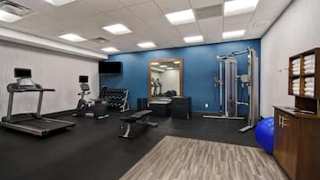 Una palestra con tapis roulant, cyclette, macchinari per l'allenamento della forza e uno specchio.