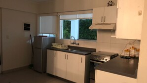 A compact kitchen with white cabinets, a built-in oven, a sink, and a window with a view of greenery outside. - Santa Maria del Mar, Terramar 315, 204 (Urb Santa Maria del Mar)
