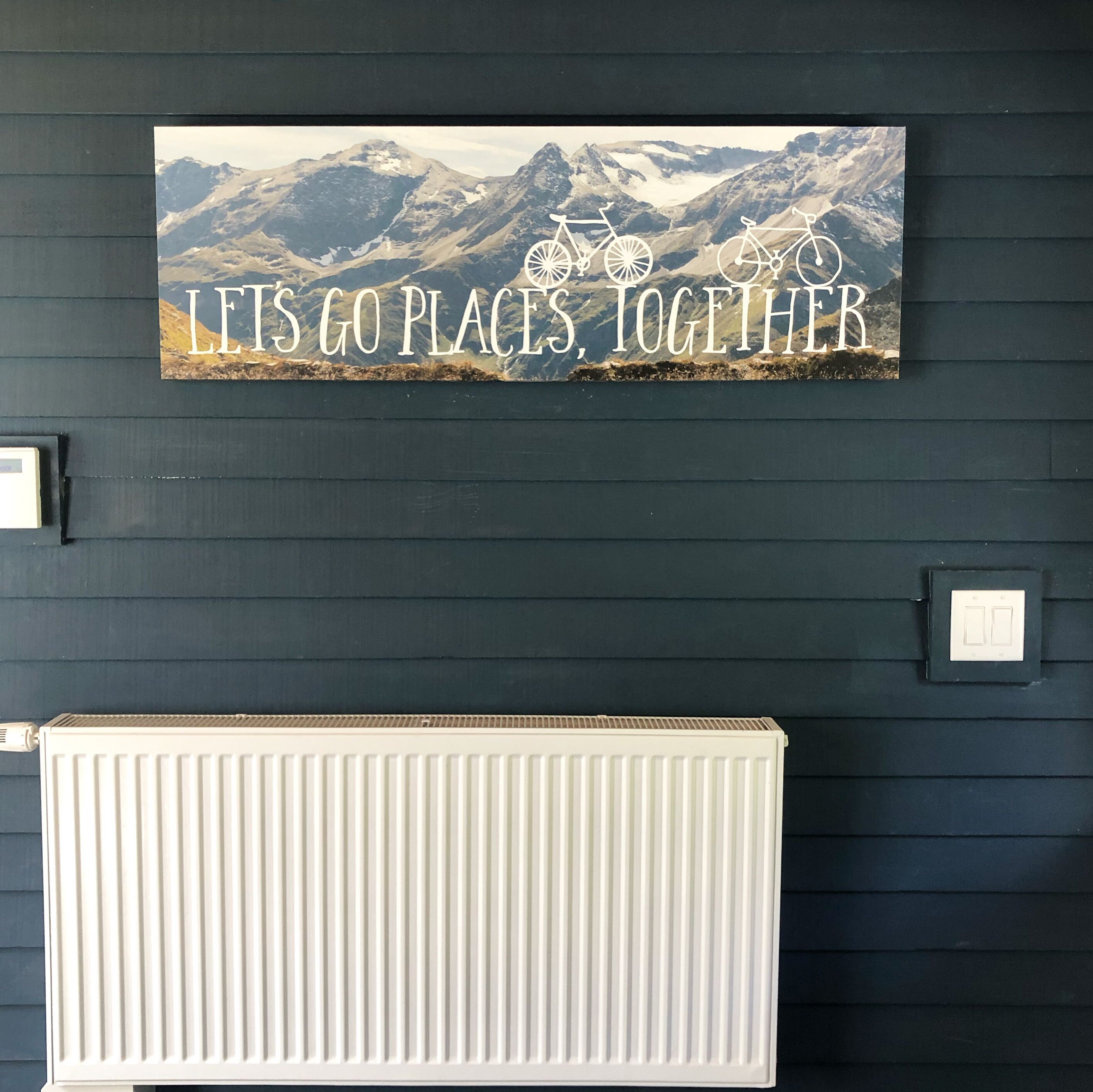 Eine Wand mit einem Motivationsschild, auf dem steht „LETS GO PLACES, TOGETHER“, und einem weißen Heizkörper darunter.