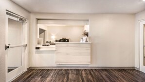 A hotel reception area with a wooden floor, a reception desk, a mirror, and a door. - WoodSpring Suites Bradenton (Bradenton)