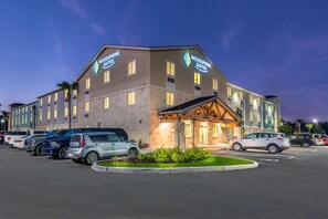 A hotel with a modern design, featuring a large parking lot and multiple vehicle types parked. - WoodSpring Suites Bradenton (Bradenton)