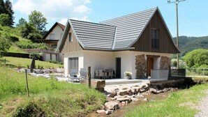 A modern house with a sloped roof, a stone facade, and a small stream in front. - Wonderful private villa for 4 people with A/C, WIFI, TV and patio (Ullerst)