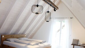 A loft bedroom with a wooden bed, two hanging light fixtures, and a view of a balcony. - Wonderful private villa for 4 people with A/C, WIFI, TV and patio (Ullerst)