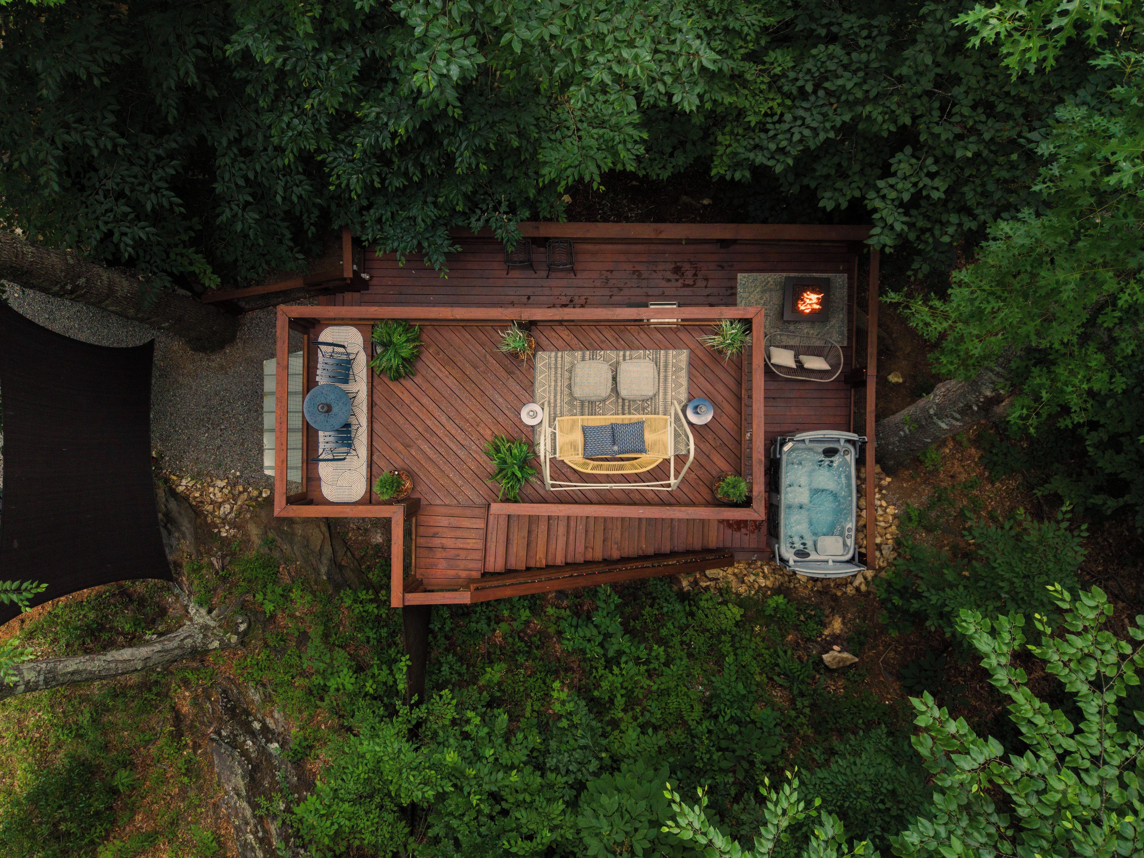 A deck with a hot tub, seating area, and a fire pit.