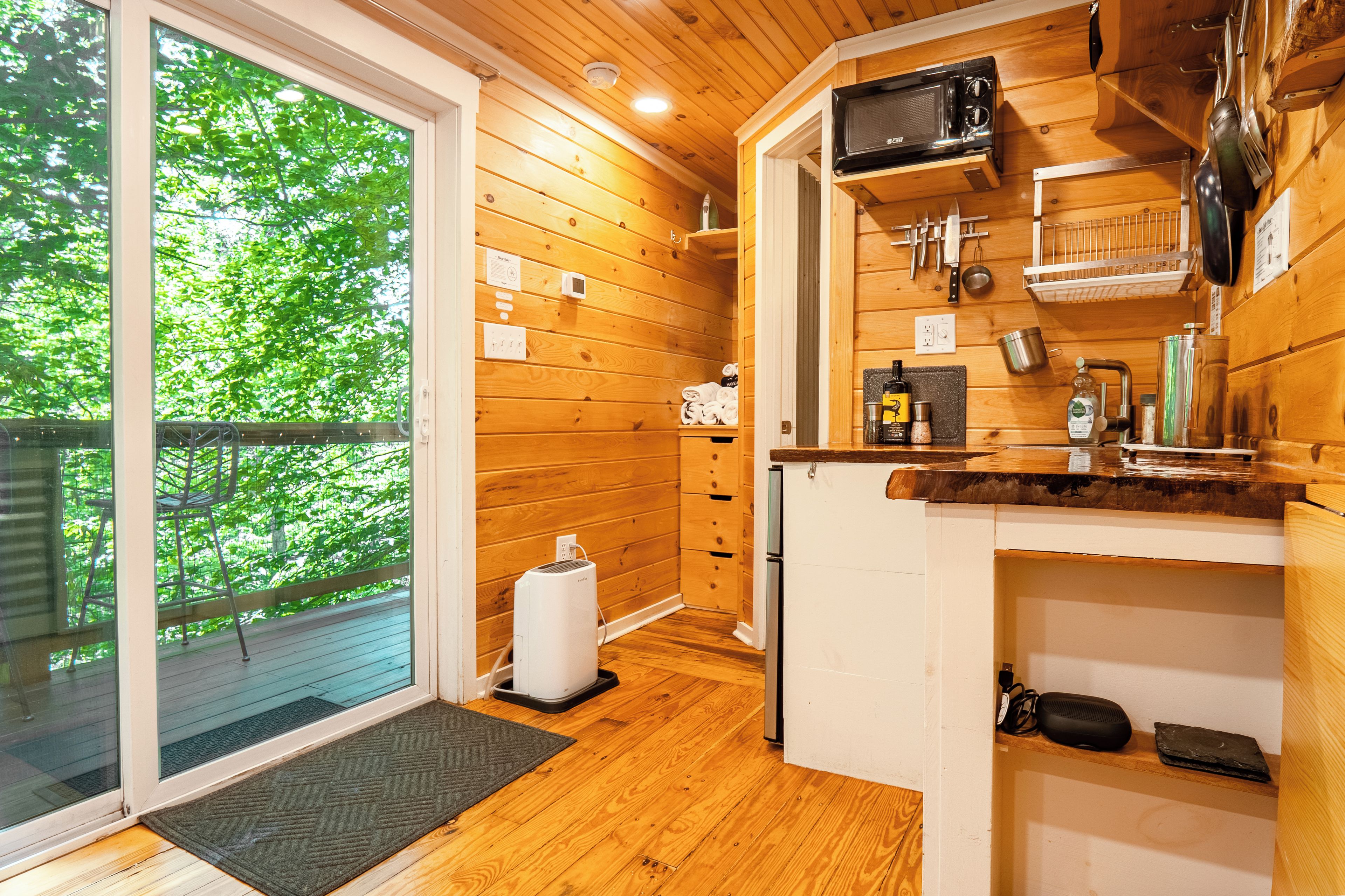 A compact kitchen with wooden walls, a built-in microwave, and a small refrigerator.