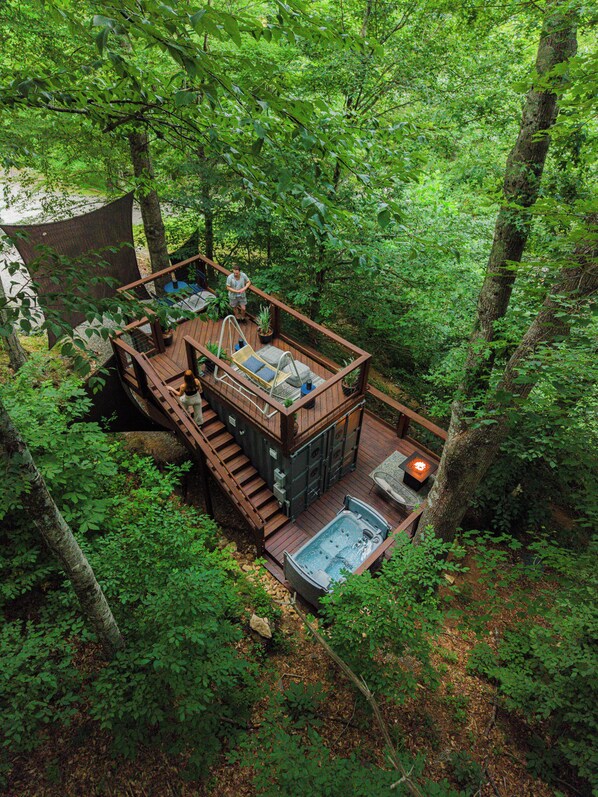 A wooden deck with a hot tub, outdoor seating, and a staircase leading to a deck area.