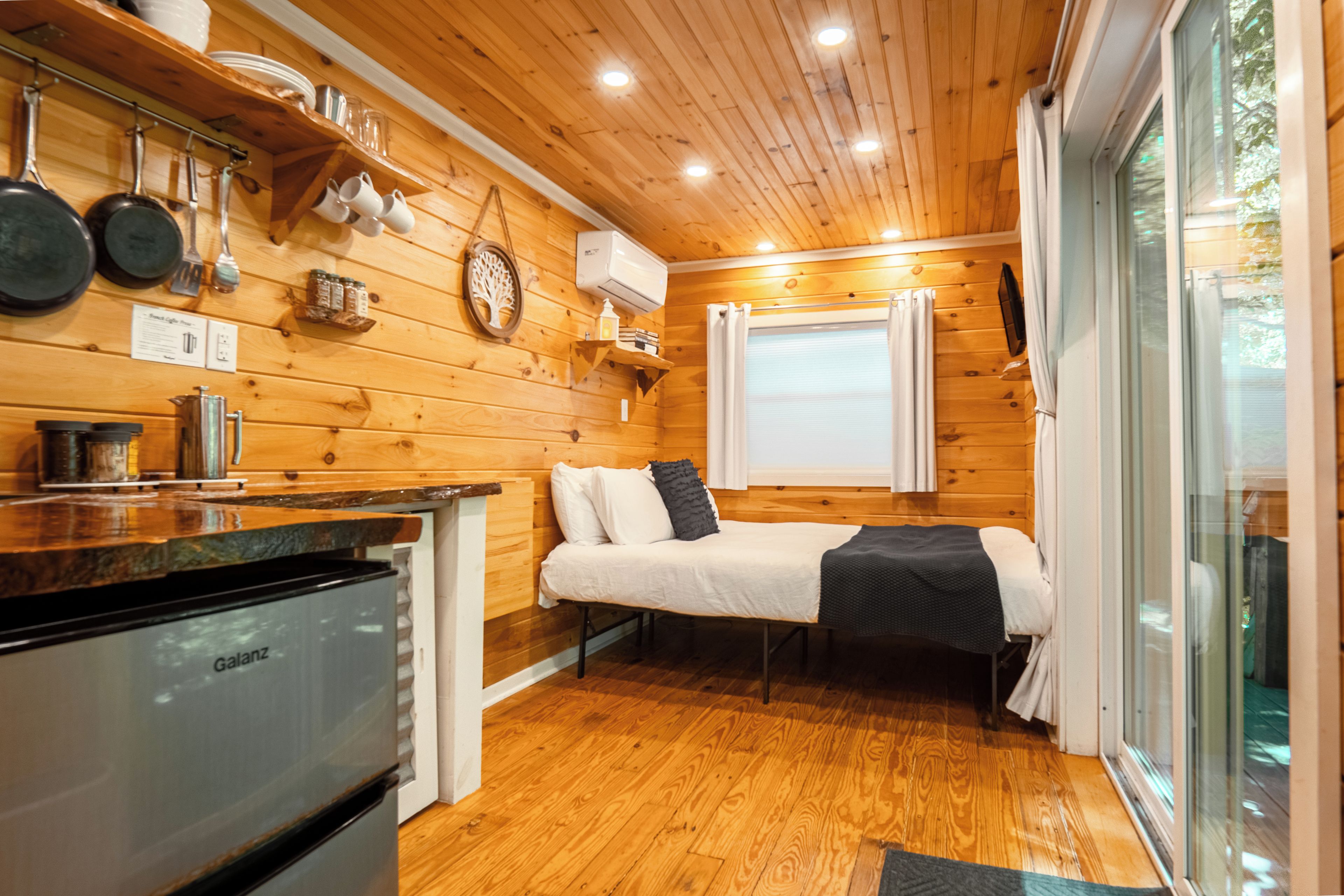 Una habitación pequeña con cama, kitchenette y ventana.