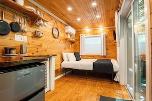 A compact room with a bed, a small kitchenette, and a window. - Tiny Container Home Retreat with Hot Tub, Fire Table, Dining Area, and Views! (Todd)