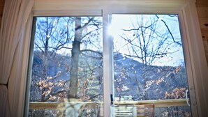 Ventana de madera con vistas a un árbol y una montaña.