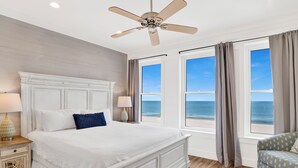 A bedroom with a large bed, a ceiling fan, and a view of the ocean through the windows. - Beachfront Luxury | Private Pool | Elevator (Gulf Shores)