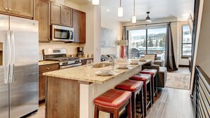A modern kitchen with stainless steel appliances, a granite countertop, and a large island with bar stools.