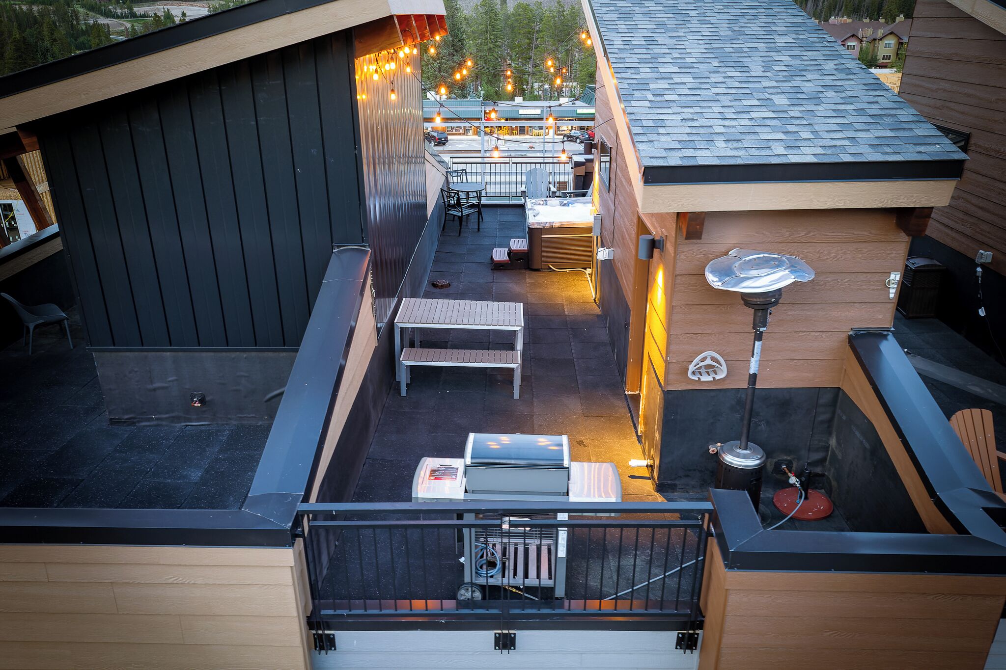 A rooftop patio with outdoor seating, a barbecue grill, and string lights.