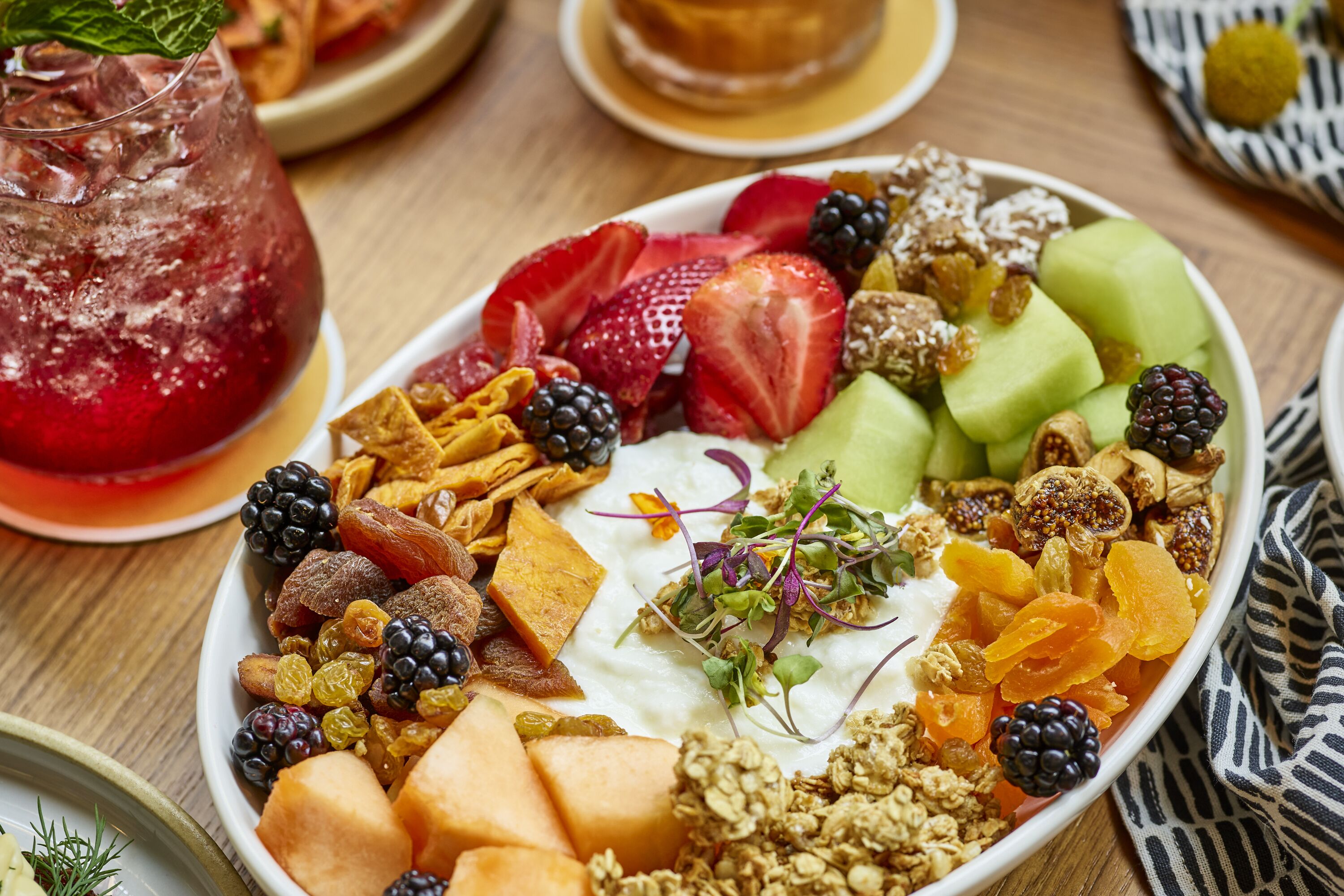 A fruit platter with various fruits and nuts on a wooden table.
