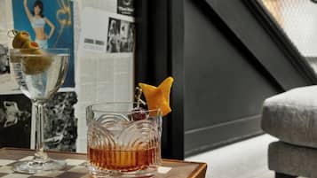 A bar area with a checkered table, two glasses of whiskey, and a poster on the wall.