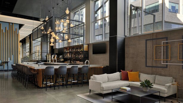 A modern interior with a bar area, seating, and a large window providing natural light.