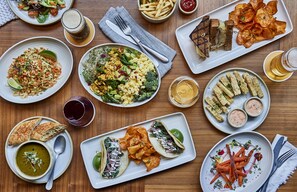 A variety of dishes including tacos, fries, and a salad on a wooden table.