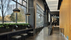 A modern interior with a long bar area, seating, and a staircase leading to an upper level.