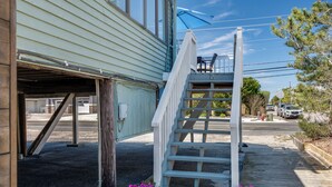 A wooden staircase leading to a porch with a white railing and a blue umbrella. - 2026 AVAILABLE!PET FRIENDLY 1BR condo OCEANFRONT Building perfect for a COUPLE!! (Long Beach Township)