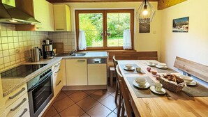 Una cocina con estufa, horno, pileta y ventana con vista a vegetación.