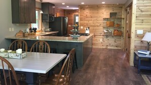 A spacious kitchen with dark wooden cabinets, a granite countertop, and a central island with seating. - Your search ends with KSW Cabin. All a group needs, incl. 5 bathrooms. Sleeps 14 (Campton)