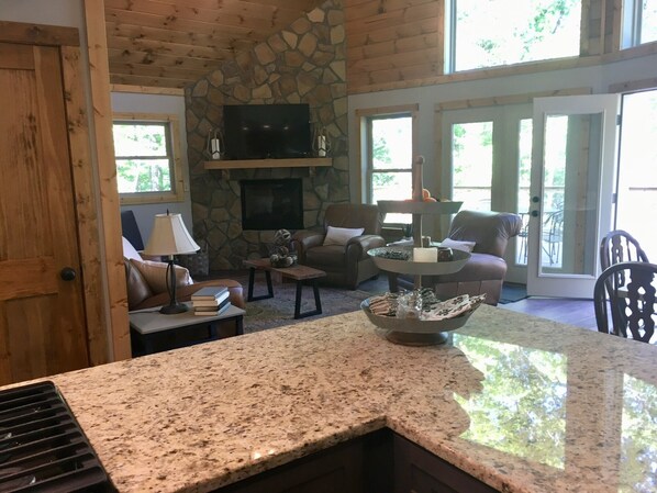 A cozy living room with a stone fireplace, comfortable seating, and a granite countertop.