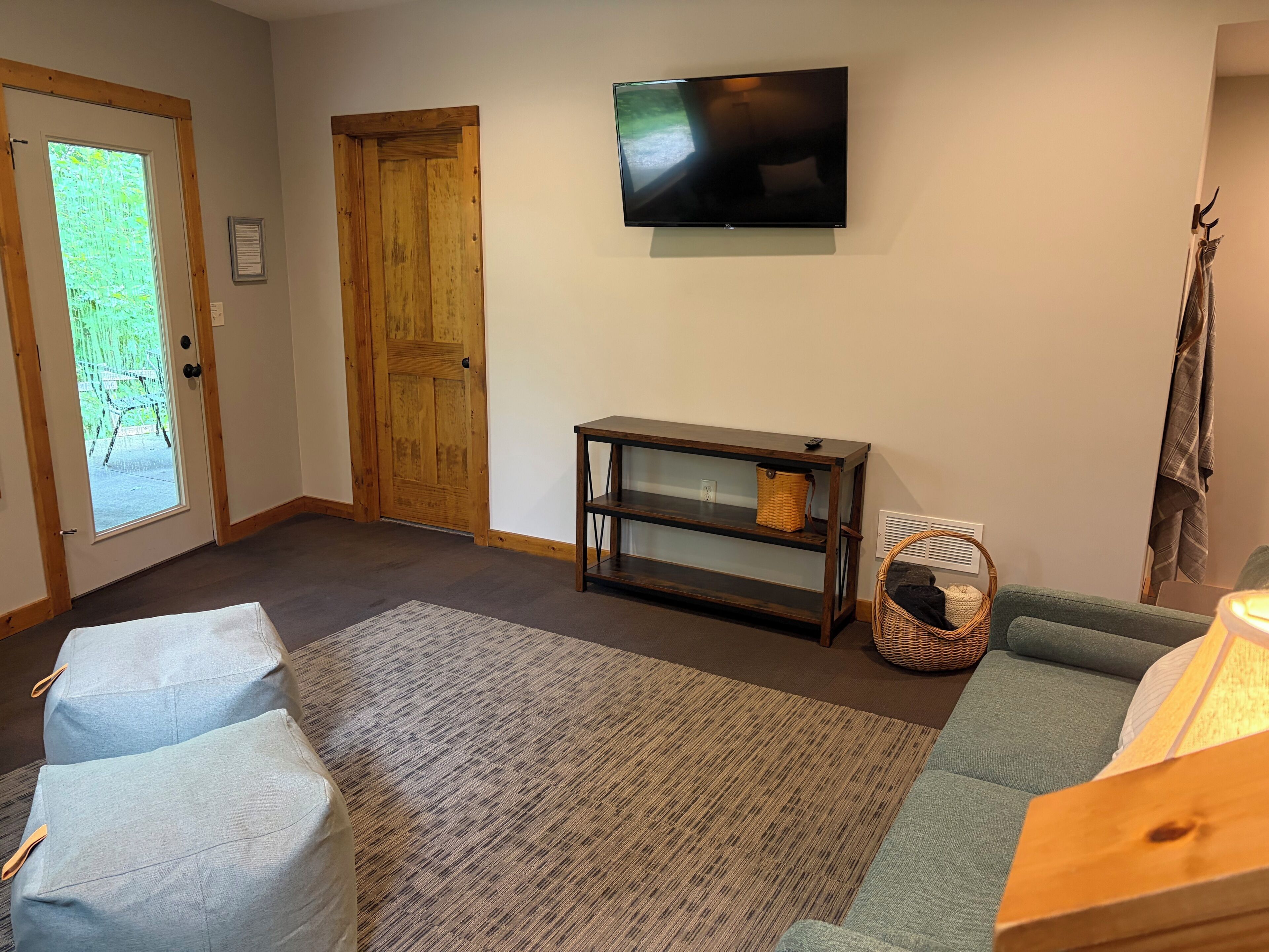 Un salon avec un téléviseur, une porte en bois, un canapé et un tapis.