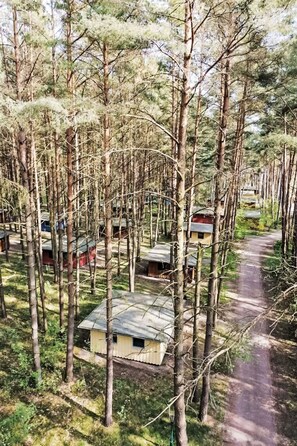 A forested area with multiple cabins, a dirt path, and a small building with a red roof. - Nice apartment in villa for 8 people with WIFI, TV and terrace (Waren)