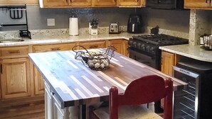 Une cuisine avec des meubles en bois, un îlot central, une chaise rouge et divers appareils électroménagers.