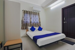 A bedroom with a bed, a bedside table, a wardrobe, and an air conditioning unit. - Silverkey Executive Stays 24138 Nallagandla (Hyderabad)