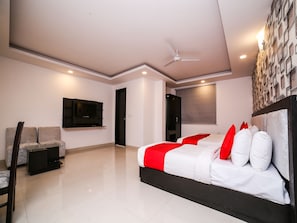 A modern bedroom with a bed, a TV, a sofa, and a ceiling fan. - OYO 24943 Belmond Palace (New Delhi)