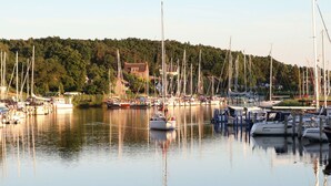 A marina with multiple sailboats docked, calm water, and a forested hill in the background. - Cosy apartment in villa for 4 guests with WIFI, TV, terrace and pets allowed (Sassnitz)