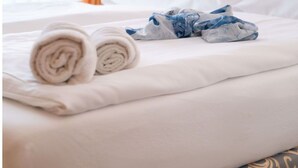 A neatly made bed with rolled towels and a pillow, a wall-mounted light, and a painting of a boat on the wall. - Cosy apartment in villa for 4 guests with WIFI, TV, terrace and pets allowed (Sassnitz)