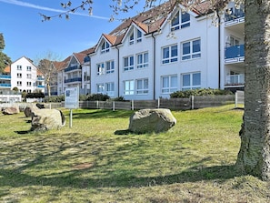 Ein mehrstöckiges Wohngebäude mit weißer Fassade und roten Ziegeldächern.