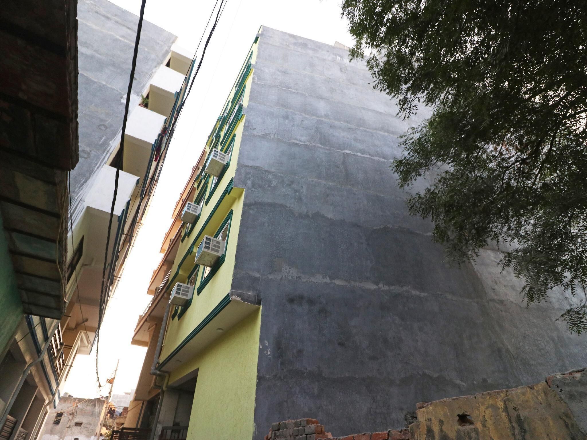 A narrow street with multi-story buildings, some with balconies and air conditioning units.