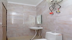 A bathroom with a toilet, sink, and mirror. - OYO 847 Hotel Sinon (New Delhi)