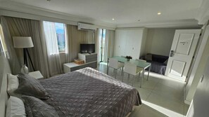 Una habitación de hotel con cama, escritorio, televisión y balcón.