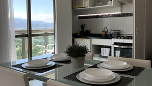Une cuisine moderne avec une table à manger en verre, des meubles blancs et une vue sur la ville.