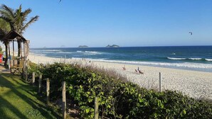 Une plage dotée d’une structure en bois, d’une clôture et offrant une vue dégagée sur l’océan et les îles lointaines.