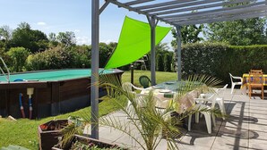 Un espace extérieur abrité comprenant une table de billard, une table avec des chaises et une structure en forme de pergola.