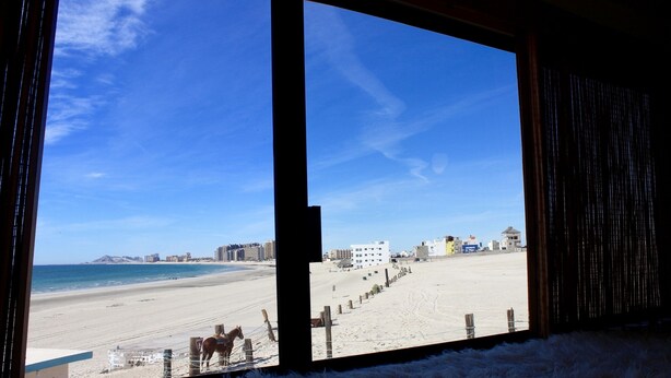 A beach view from inside a building with a large window.